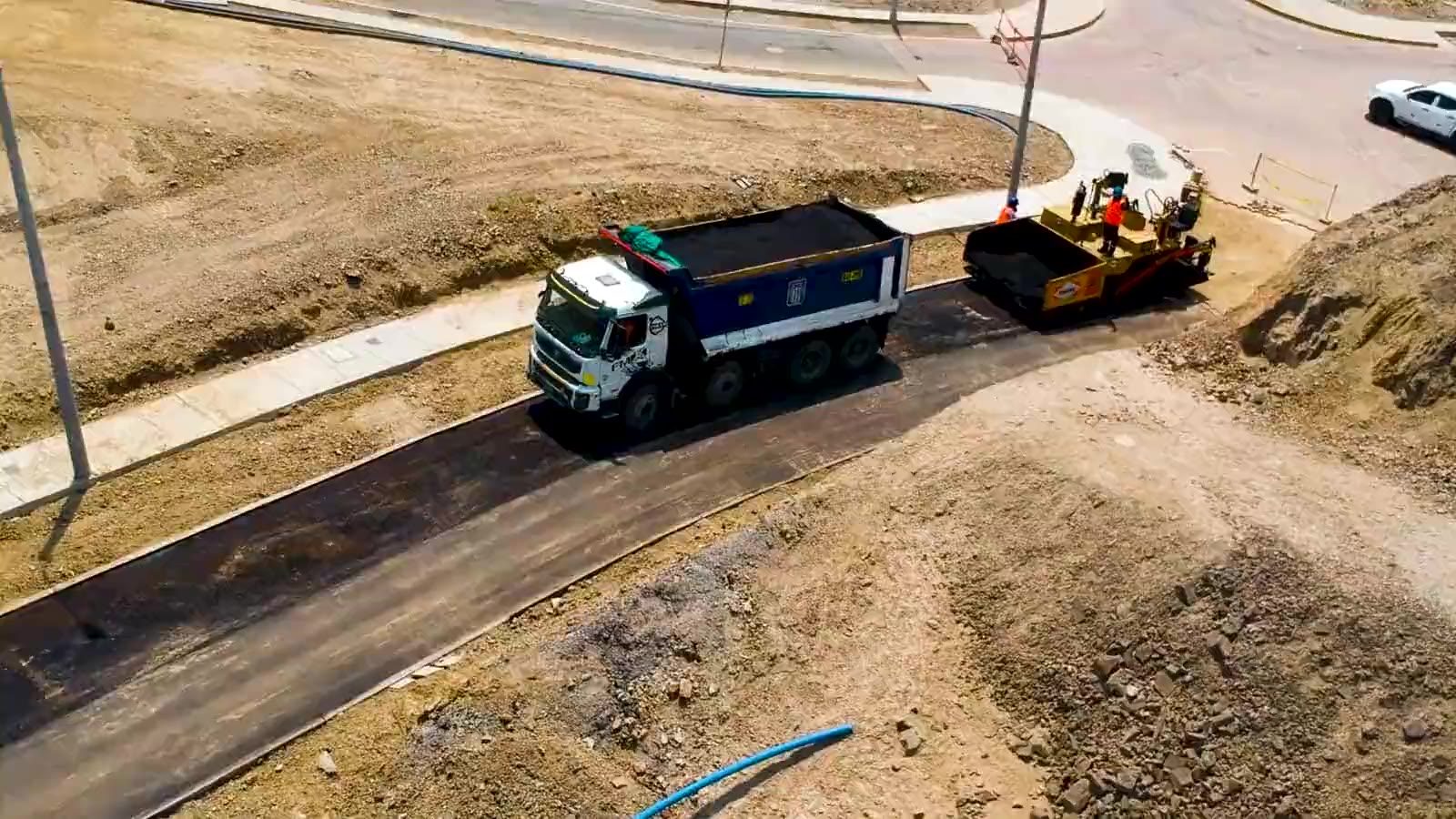 Vista aérea de una pavimentadora tendiendo carpeta asfáltica sobre un camino nuevo